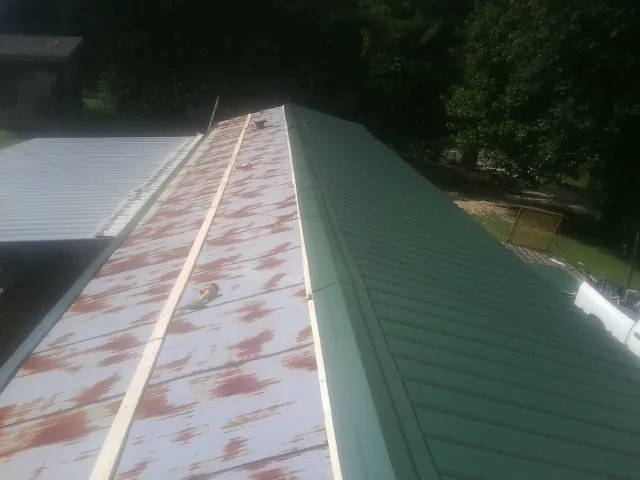 Old rusted panels beside newly installed green metal roofing — Wind Damage Roof Repair by Roofing Brothers in Rochester